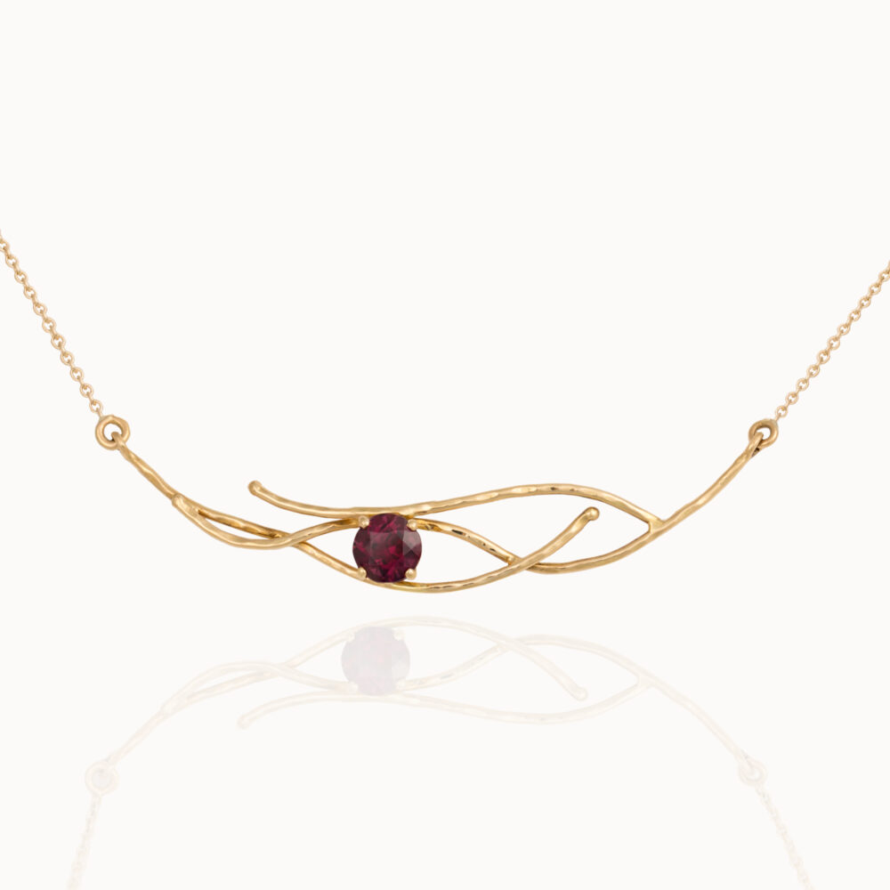 Necklace crafted from 18-karat gold set with a round cut garnet gemstone.